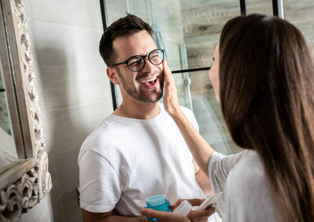 istock Young couple going through morning routine in the bathroom applying face cream. 1362786404