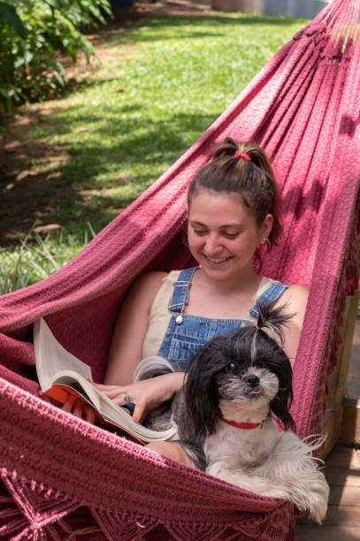 istock woman lying in a hammock, reading a book with a dog 1362786676