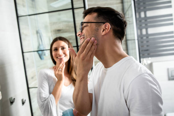 istock Young couple going through morning routine in the bathroom applying face cream. 1362786709