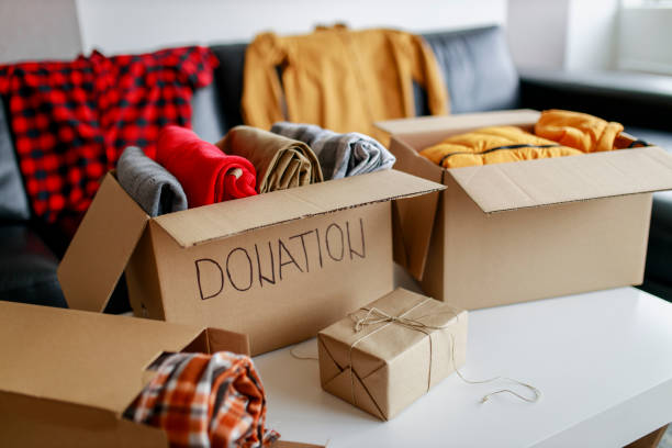 boîte de dons avec des choses (couvertures et vêtements) - don caritatif photos et images de collection