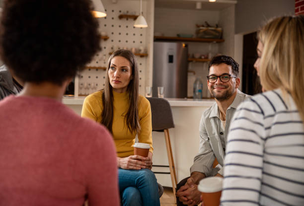 istock Diverse group of people sitting in circle in group therapy session. 1362787644