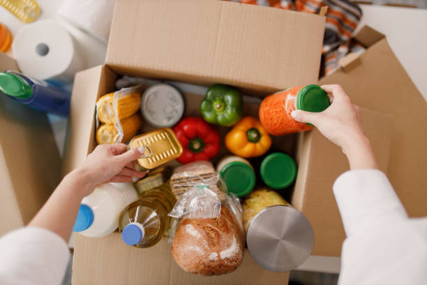 details of volunteer with box of food for poor - schenking stockfoto's en -beelden