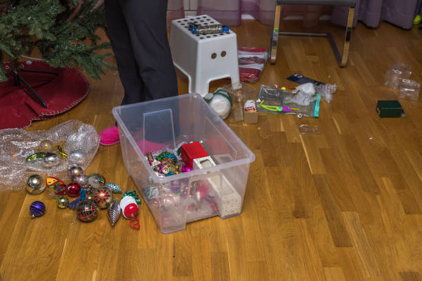 Close up view of woman's feet near plastic box with Christmas tree decoration toys. Undecorating of Christmas tree. Sweden. Close up view of woman's feet near plastic box with Christmas tree decoration toys. Undecorating of Christmas tree. Sweden. christmas decoration storage stock pictures, royalty-free photos & images