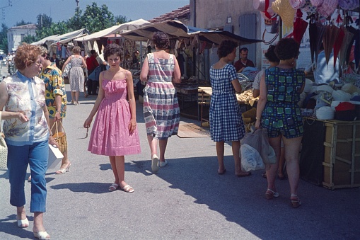 Rimini Region, Emilia Romagna, Italy, 1961. Tourists visit a clothing market. Furthermore: stands, goods and sellers.