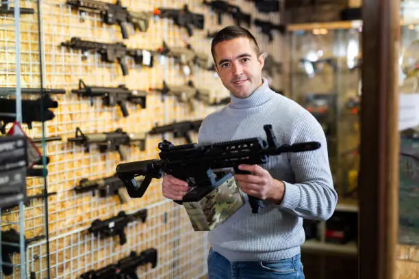 Photo of Man with machine gun in arms shop