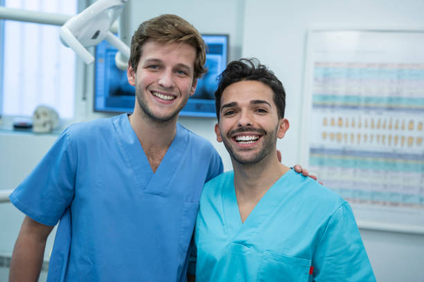 Two young fellow dentists smiling in the dental clinic Two young fellow dentists smiling with uniform in the dental clinic dental hygienist stock pictures, royalty-free photos & images