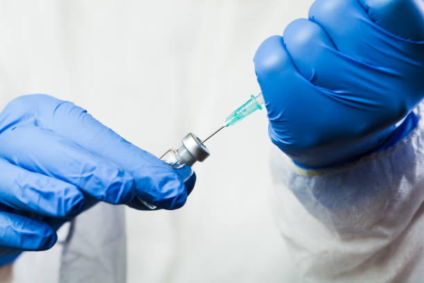 primer plano de la jeringa con aguja en el vial de la ampolla de la vacuna - antiinflamatorio fotografías e imágenes de stock