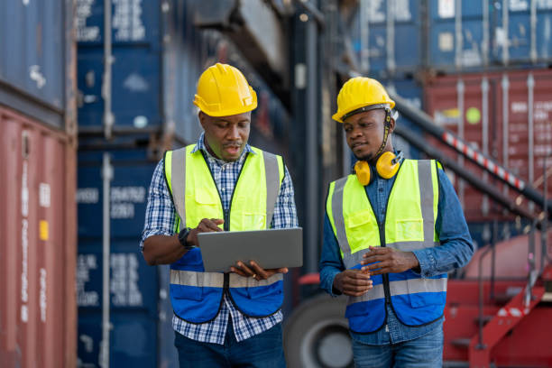 istock African workers, Engineer, Technician holding laptop for checking and inspecting on site containers area for shipping transportation and machine lifting. Concept people operation in heavy industrial. 1362794625