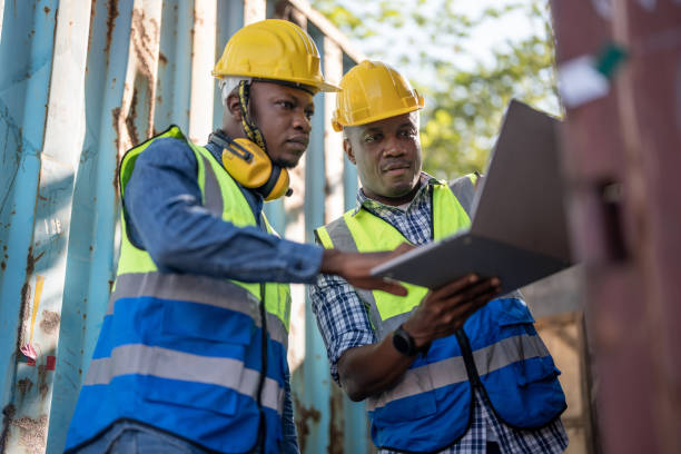 istock African workers, Engineer, Technician holding laptop for checking and inspecting on site containers area for shipping transportation. Concept people operation in heavy industrial. 1362795524
