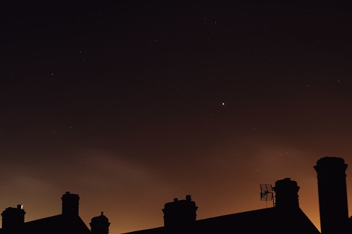 Rooftops and chimneys at night with stars and light pollution from parkhurst prison