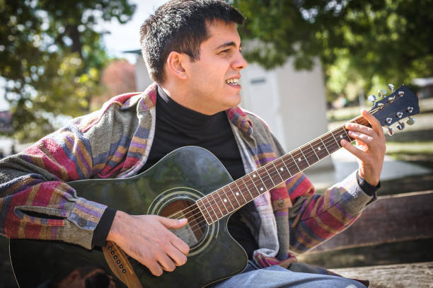 istock Young man play solo guitar while sitting on park bench 1362810825