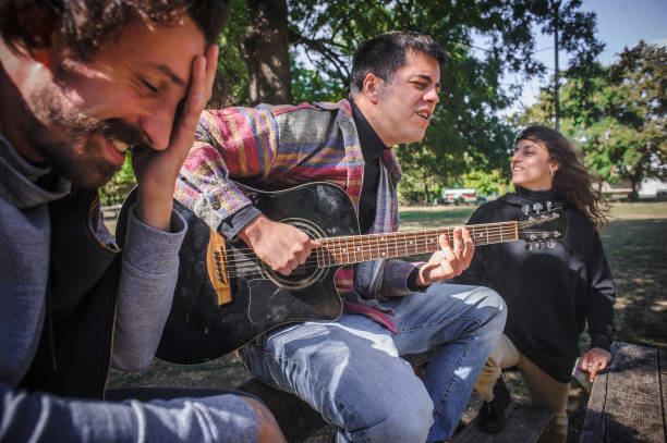 istock Friends play guitar and singing together while sitting on bench 1362810867