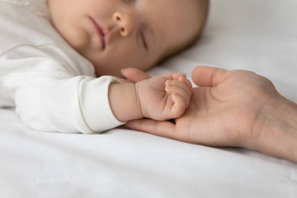 istock Close up loving mother holding sleeping small baby hand 1362814023
