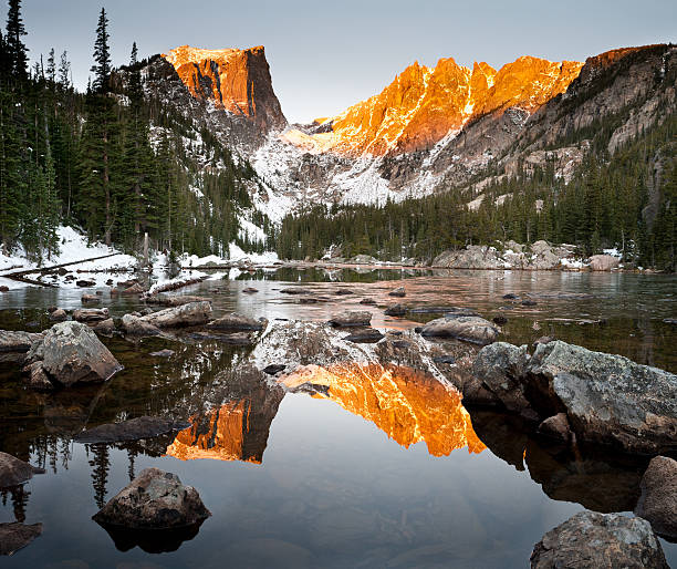 Dream Lake and Hallet Peak Alpenglow Reflection Sunrise on a calm October morning creates a warm alpenglow on Hallet Peak.  The still waters of Dream Lake reflect the mountains perfectly in the water.  Taken at Rocky Mountain National Park, Colorado. rocky mountain national park photos stock pictures, royalty-free photos & images
