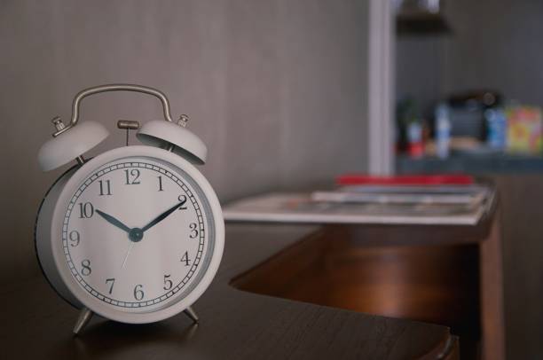 istock Retro alarm clock on table with blurred living room background 1362821171