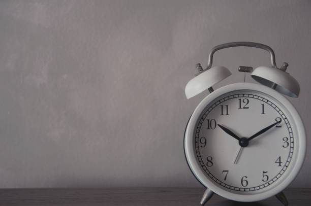 istock Retro alarm clock on table with blurred living room background 1362821191