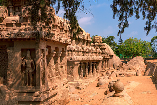 Image shows the Dharmaraja, Bhima, Arjuna and Draupadi Rathas all lined up. Four of the five Pancha Rathas (also known as Pandava Rathas), a monument complex at Mahabalipuram or Mamallapuram, on the Coromandel Coast of the Bay of Bengal, in the state of Tamil Nadu, India. Dating from the late 7th century, it is attributed to the reigns of King Mahendravarman I and his son Narasimhavarman I (630-680 AD) of the Pallava Kingdom. The structures are without any precedence in Indian temple architecture and are carved out of a single granite rock each. Remarkably well preserved, they withstood the ravages of the Tsunamis of the 13th Century and 2004. They however display the effects of wind and sand erosion of over one thousand three hundred years. These are not temples as they are unfinished, and were never consecrated. They are part of the UNESCO World Heritage site at Mahabalipuram. Photo shot in the afternoon sunlight; horizontal format.