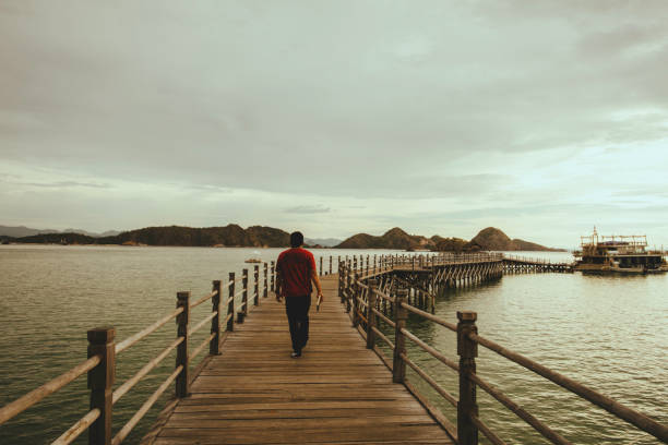 Back view of man walking on boardwalk