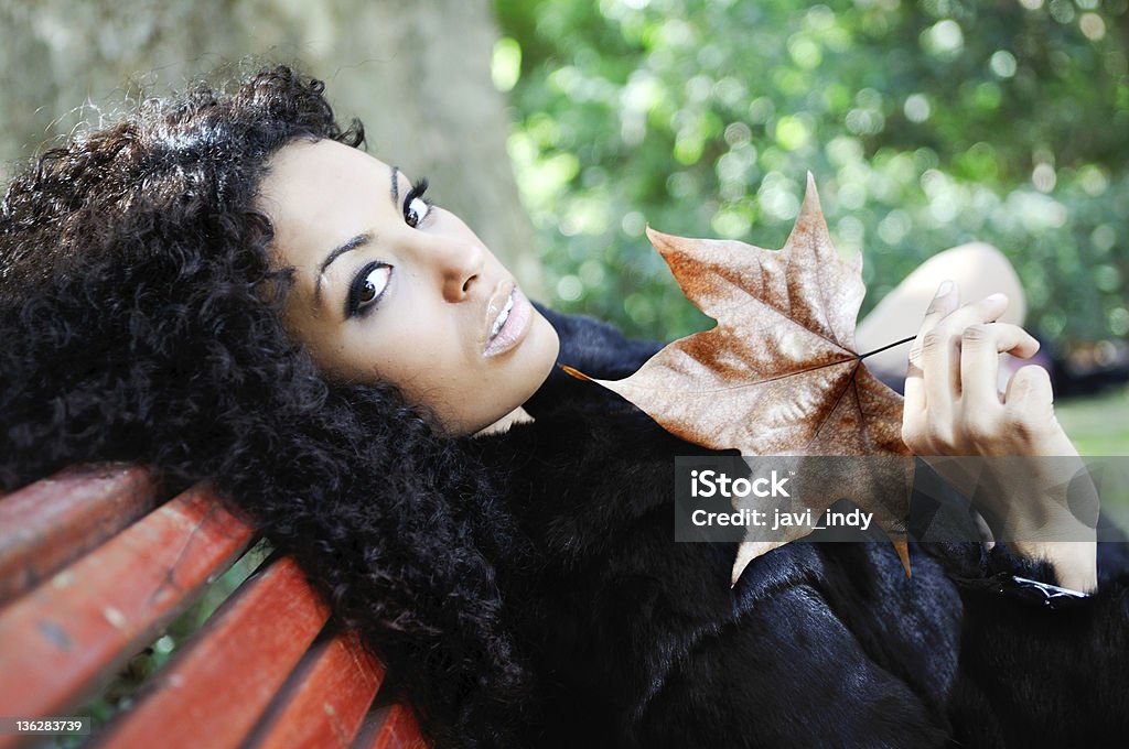 Jovem bela mulher negra, localização no banco no parque - Royalty-free Bronze - Cores Foto de stock