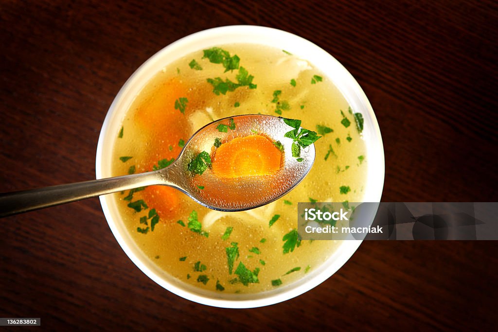 Traditional chicken soup A picture of a bowl of traditional chicken soup served in a bowl over wooden background Chicken Soup Stock Photo
