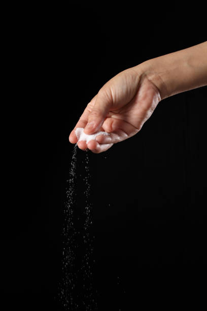 istock Hand holding salt on black background 1362840869