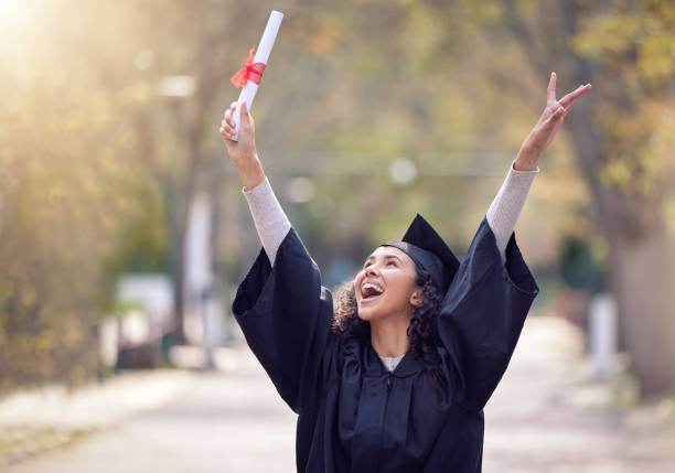 shot of a young woman cheering on graduation day - toga stockfoto's en -beelden