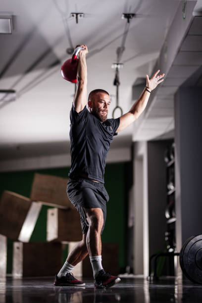 istock Muscular athlete power lifting a kettlebell. Man working out indoors 1362842448