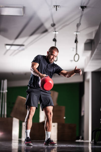 istock Muscular athlete power lifting a kettlebell. Man working out indoors 1362842454