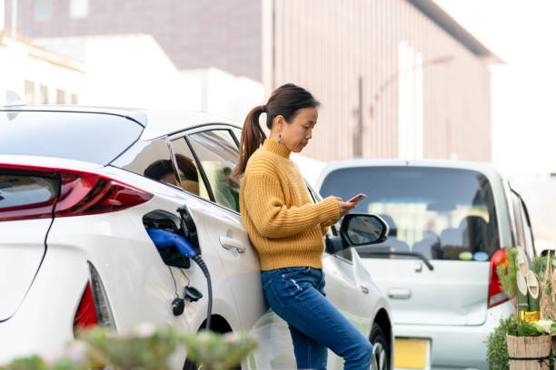 istock Woman charging electric car while using mobile phone 1362844513