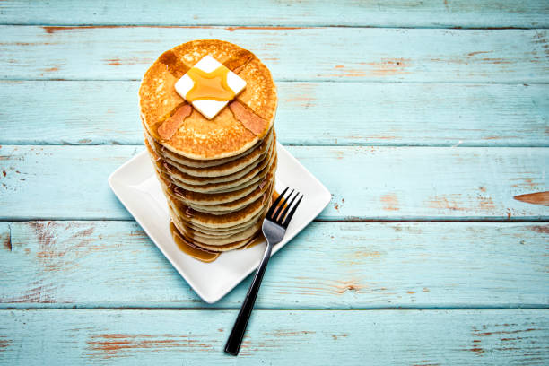 This is a photograph of a large tall stack of pancakes on a blue picnic background