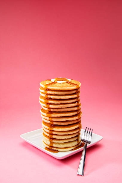 Big Tall Stack of Pancakes on Pink Background This is a photograph of a large tall stack of pancakes on a pink background pancake photos stock pictures, royalty-free photos & images
