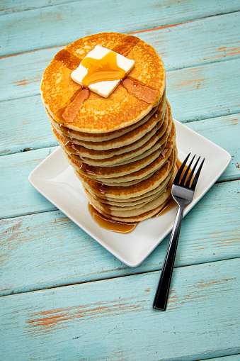 This is a photograph of a large tall stack of pancakes on a blue picnic background