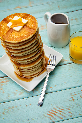 This is a photograph of a large tall stack of pancakes on a blue picnic background