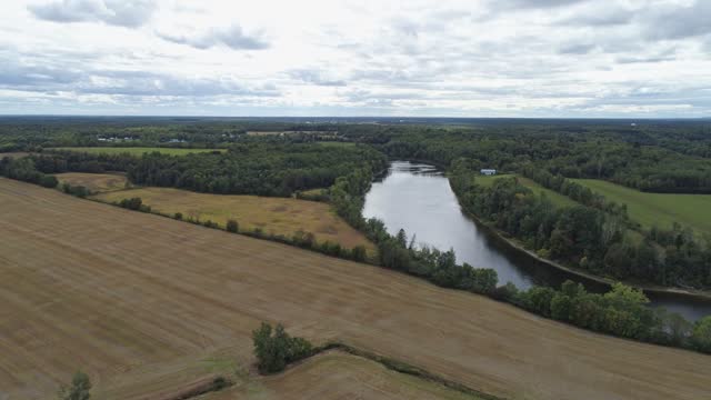 High aerial drone view, moving toward Batiscan river above an agricultural field in the country of Sainte-Genevieve-de-Batiscan