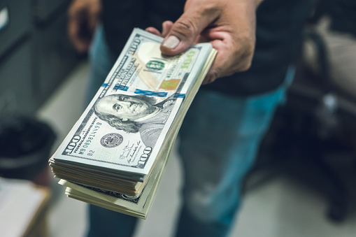 Closeup shot of businessman hand holding American dollars cash with copy space. Financial money income or profit incentive corporate concept. Receiving illegal payoff.