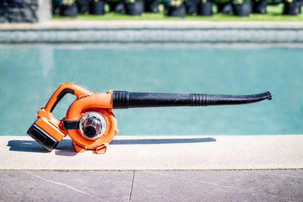Cordless leaf blower or sweeper in front of a pole, outside.