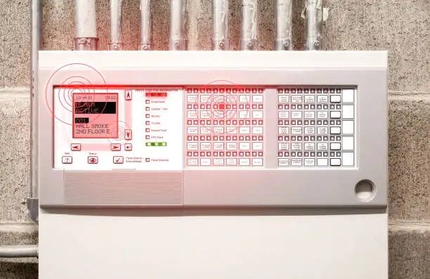 Control panel display with smoke alarm message and flashing red lights. Fire control panel in electrical room of residential and commercial building.