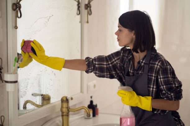 istock Young woman is washing mirror in the bathrom. 1362859918