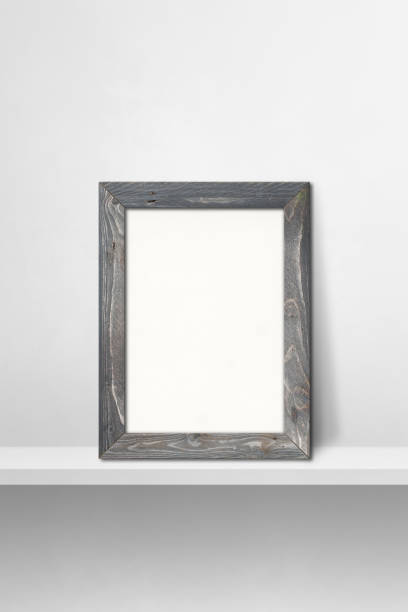 istock Wooden picture frame leaning on a white shelf. 3d illustration. Vertical background 1362863759