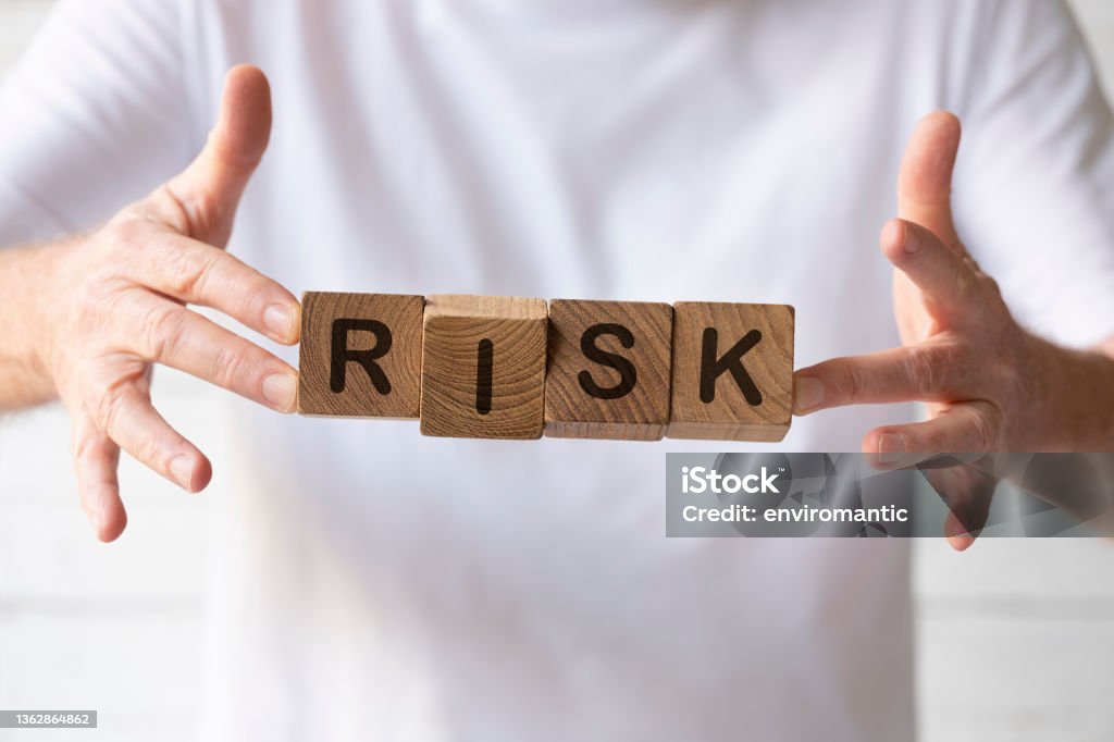 Natural teak wood blocks with the word 'Risk' written on them, being held up by a man. Concept image relating to risk, uncertainty, business concepts, opportunity, investment, etc. Venture Capital Stock Photo