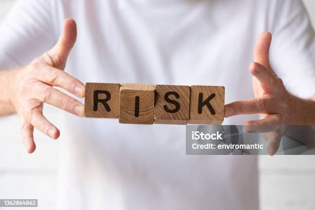 Natural Teak Wood Blocks With The Word Risk Written On Them Being Held Up By A Man Stock Photo - Download Image Now