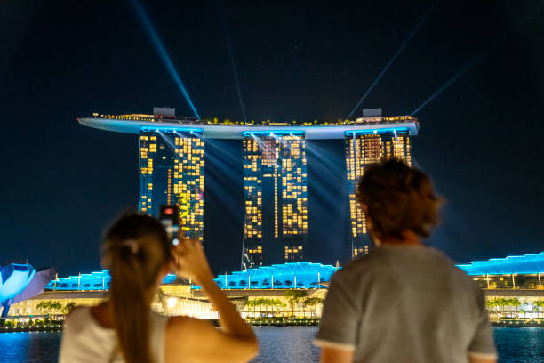 casal vendo raios de luz radiante do topo de marina bay sands, cingapura - singapore skyline - fotografias e filmes do acervo