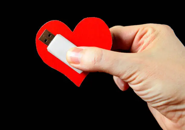 Heart Shape and USB Drive in the Hand on the Black Background