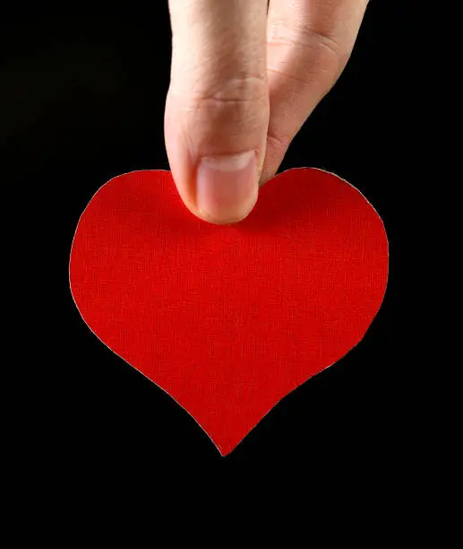 Red Heart Shape in the Hand on the Black Background