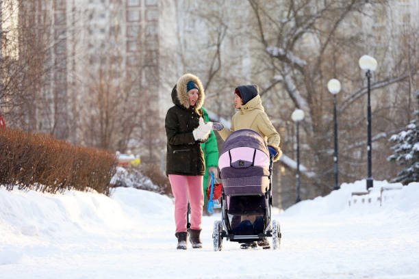 due donne che camminano con carrozzina nella città invernale - cold discussion outdoors snow foto e immagini stock