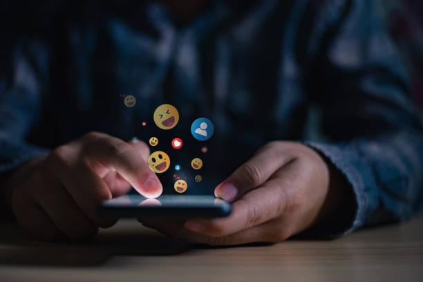 young man using smartphone sending emojis, diverse positive emoji coming out of mobile phone. mobile application for chatting, creative image, social media concept. - volgen activiteit stockfoto's en -beelden