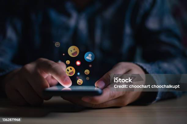 Young Man Using Smartphone Sending Emojis Diverse Positive Emoji Coming Out Of Mobile Phone Mobile Application For Chatting Creative Image Social Media Concept Stock Photo - Download Image Now