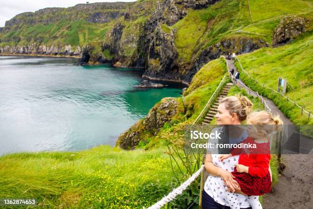 Toddler Girl And Mother On Carrickarede Rope Bridge Famous Rope Bridge Near Ballintoy Northern Ireland On Irish Coastline Family Of Child And Woman On Bridge To Small Island On Cloudy Day Stock Photo - Download Image Now