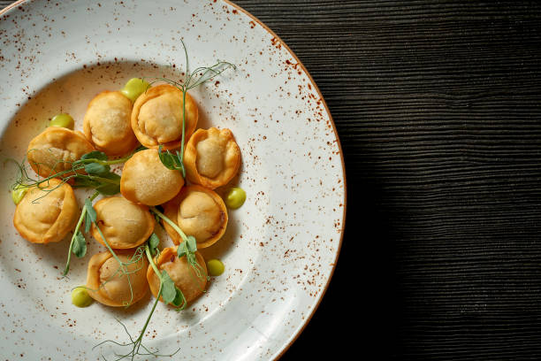 A classic Chinese dish - fried dumplings with meat and white sauce on a wooden background.