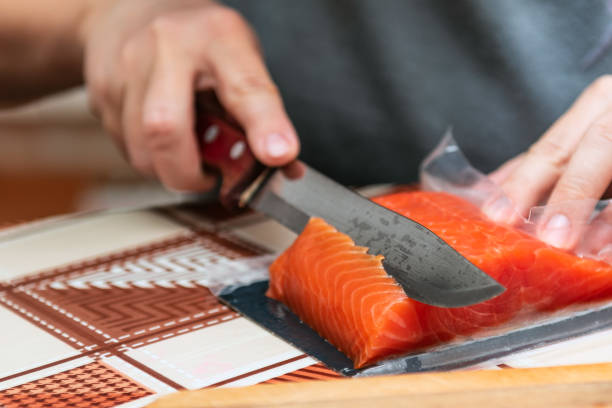 istock Hand with a knife cuts red salmon fish for sushi 1362875693